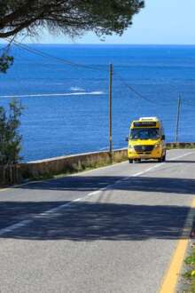 Estrada com autocarro, ao fundo mar.